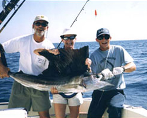 three people on a fishing boat each holding onto the same fish