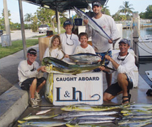 family holding caught fish in front of L&H sign