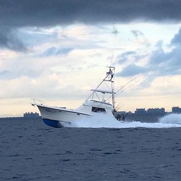 white boat on the water under dark clouds